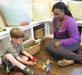 A woman and a young boy playing with toys in a room.