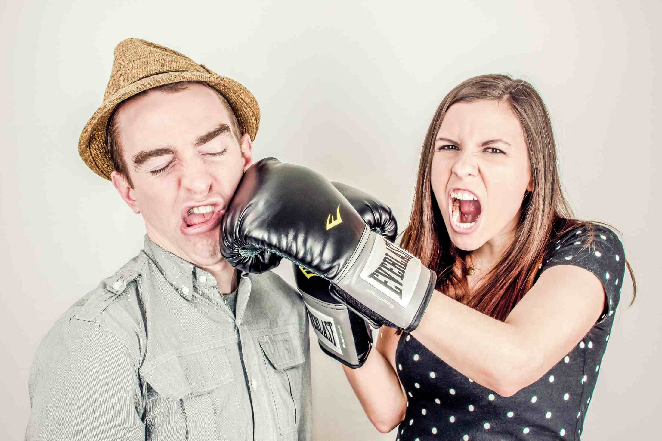 A man is punching a woman with a boxing glove.