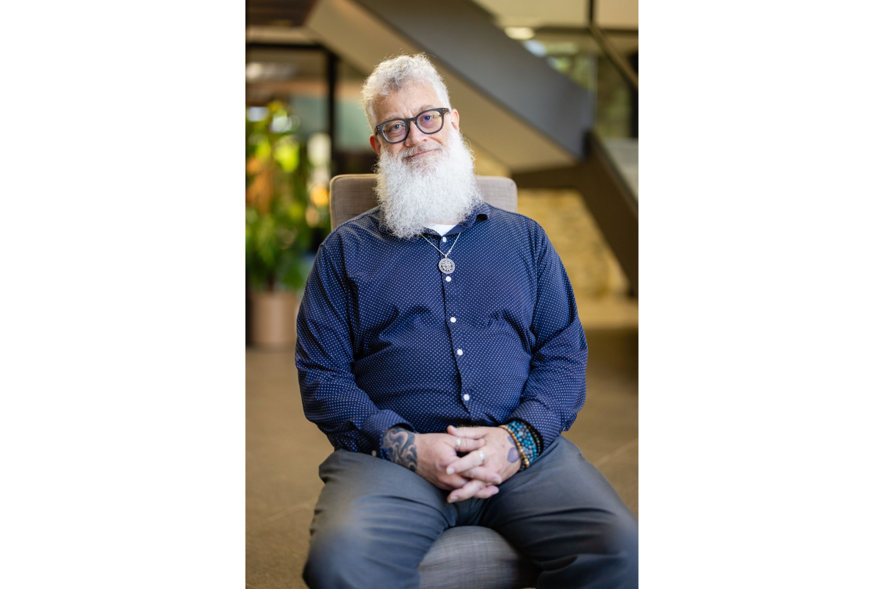 A man with white beard sitting in an office.
