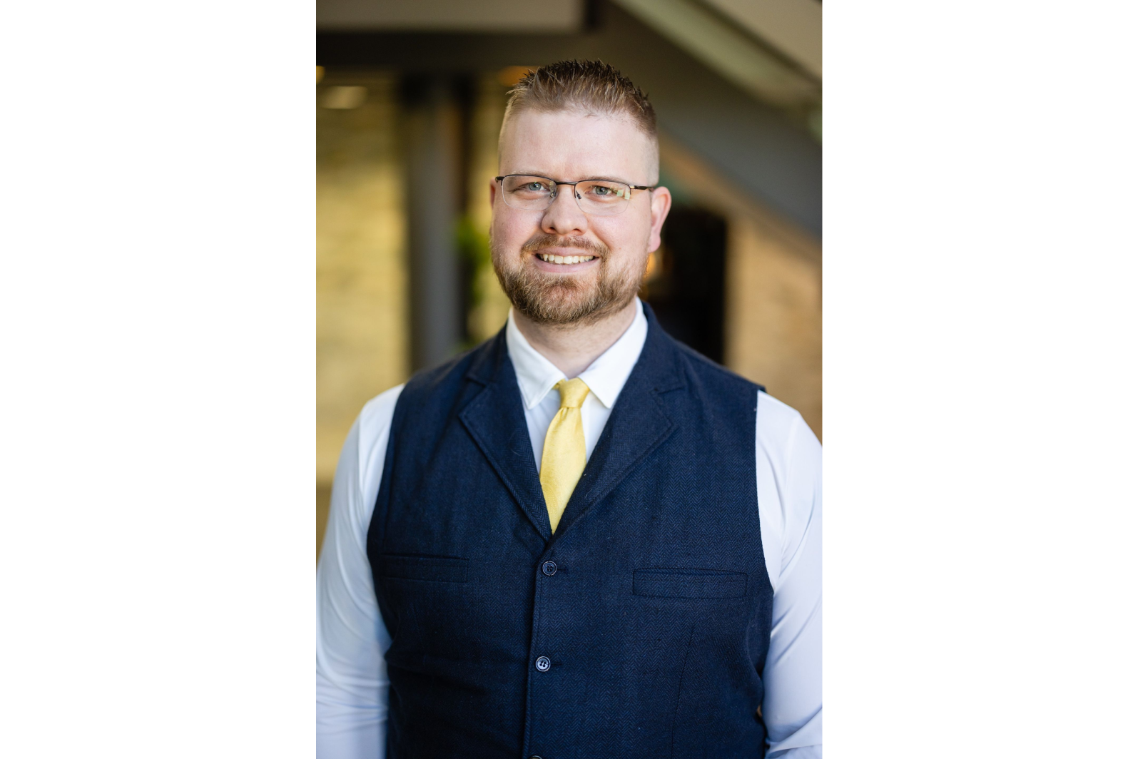 A man in vest and tie standing outside.