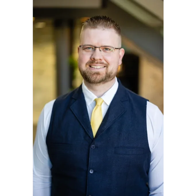 A man in vest and tie standing outside.